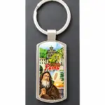 Portachiavi metallo argentato con santuario di Paola e San Francesco in preghiera su sfondo verde