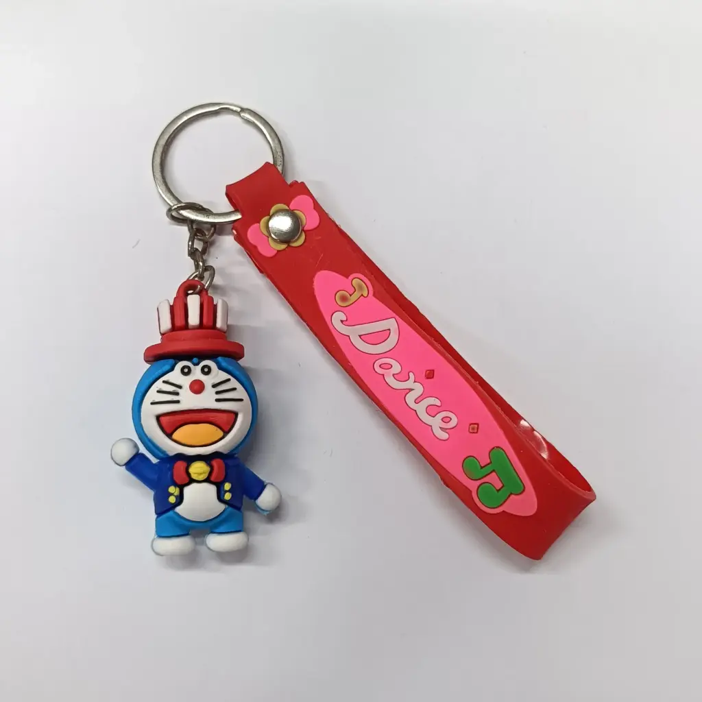 Portachiavi Doraemon blu con cappello rosso e fascetta Dorica rosa su sfondo bianco