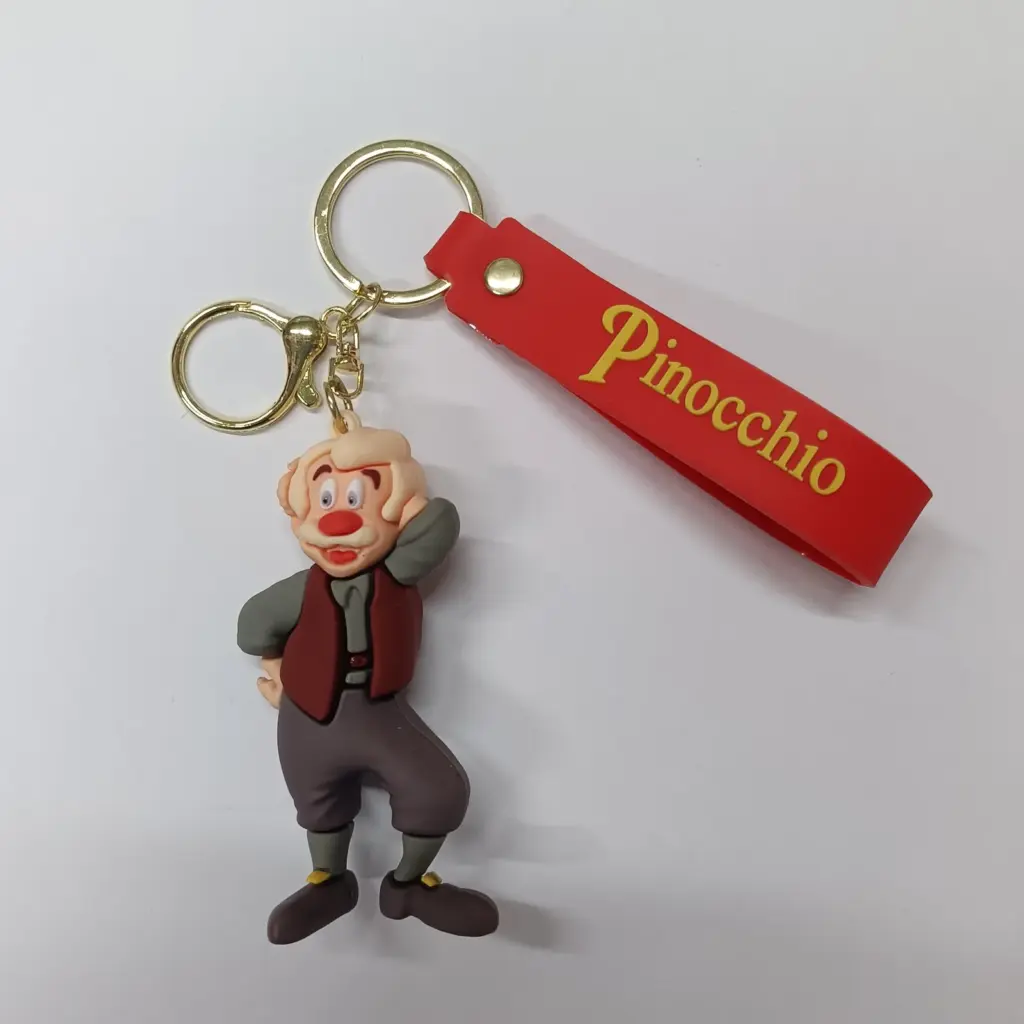Portachiavi Pinocchio in resina con gilet bordeaux, giacca grigia e targhetta rossa con scritta oro