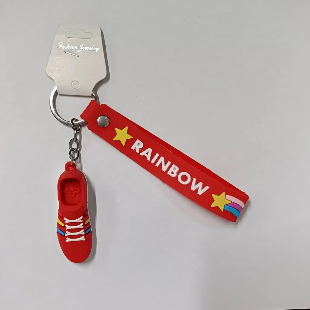 Portachiavi sneaker rossa in gomma con nastro Rainbow e stelle gialle su sfondo neutro