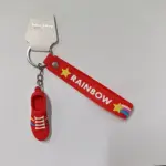 Portachiavi sneaker rossa in gomma con nastro Rainbow e stelle gialle su sfondo neutro
