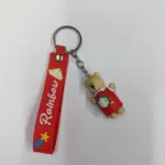 Portachiavi rosso orsetto con striscia similpelle e ciondolo beige su sfondo neutro