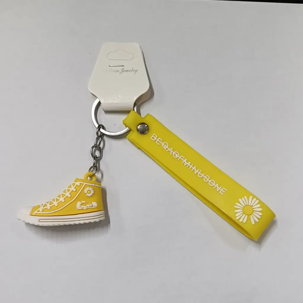 Portachiavi sneaker gialla con dettagli bianchi e linguetta decorativa con margherita