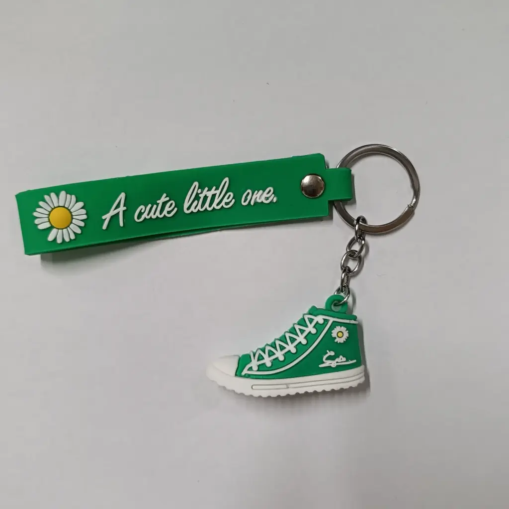 Portachiavi sneaker verde con fascetta gomma margherita gialla e bianca su sfondo neutro