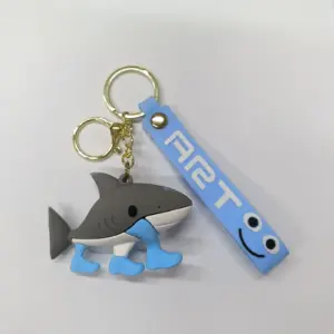 Portachiavi squalo grigio in gomma con pinne azzurre e targhetta azzurra con faccina sorridente