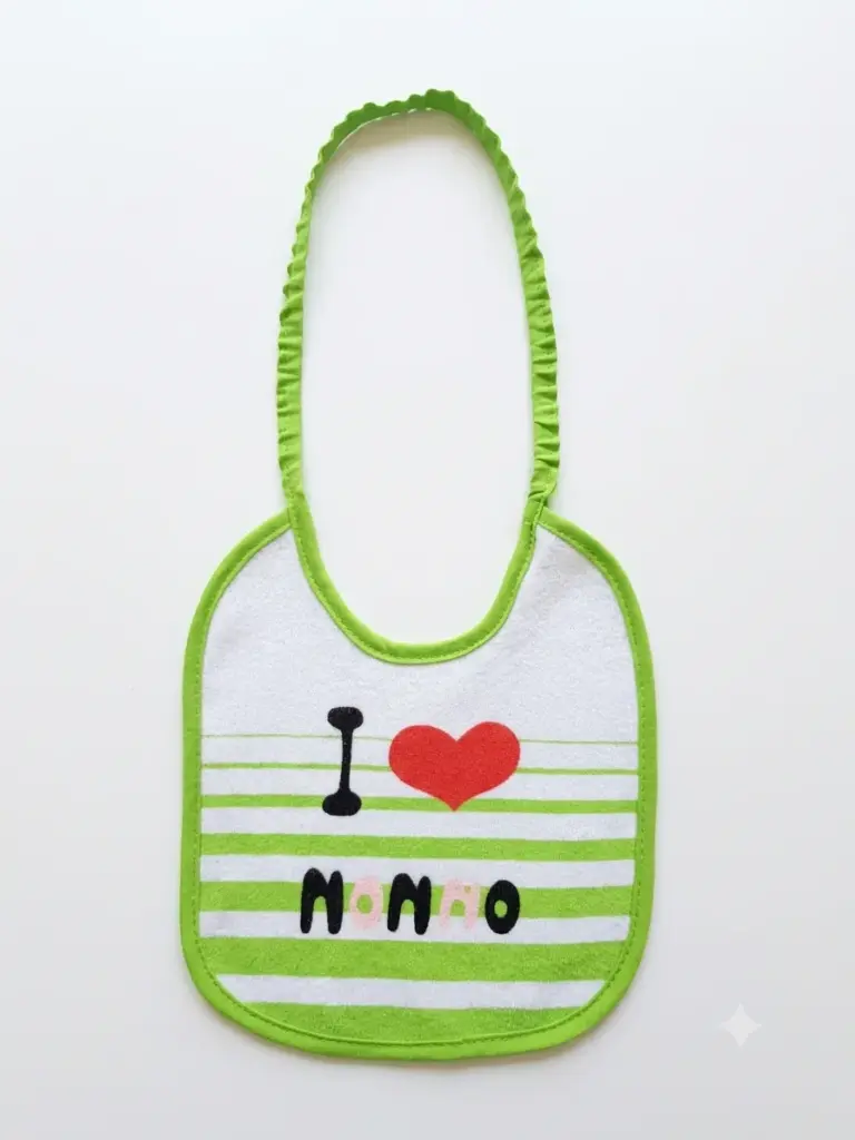 Bavetta neonato bianca con bordi verde lime, laccetto elastico arricciato e scritta I Love Nonno con cuore rosso su righe verdi e bianche.