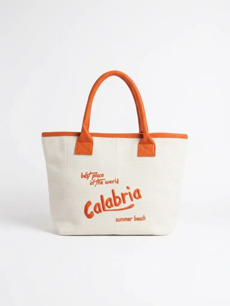 Shopper in tessuto avorio a trama fitta con manici arancioni e ricamo arancio best place in the world Calabria summer beach sul fronte