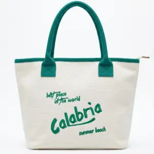 Borsa tote bianca con manici verde smeraldo e scritta Calabria best place in the world summer beach in corsivo verde sul fronte, chiusura a zip