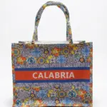 Borsa shopper in tessuto con pattern maioliche multicolori, fascia arancio con scritta CALABRIA in bianco e manici a fantasia