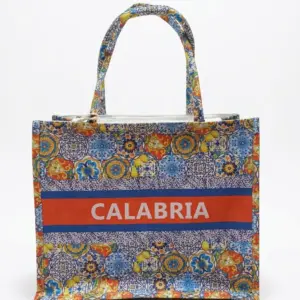 Borsa shopper in tessuto con pattern maioliche multicolori, fascia arancio con scritta CALABRIA in bianco e manici a fantasia
