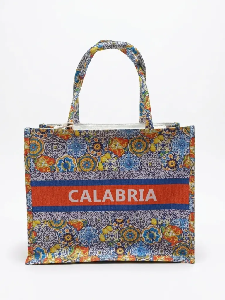 Borsa shopper in tessuto con pattern maioliche multicolori, fascia arancio con scritta CALABRIA in bianco e manici a fantasia