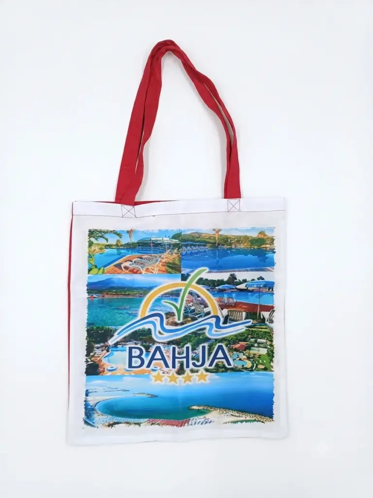 Borsa tote bianca in tela con manici rossi e stampa fotografica multicolore, logo Villaggio Bahja con palma, onde e scritta BAHJA in blu