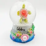 Bolla di vetro con tartaruga marina in resina, guscio rosato glitterato e pinne giallo-verdi, base decorata con perla e scritta Calabria