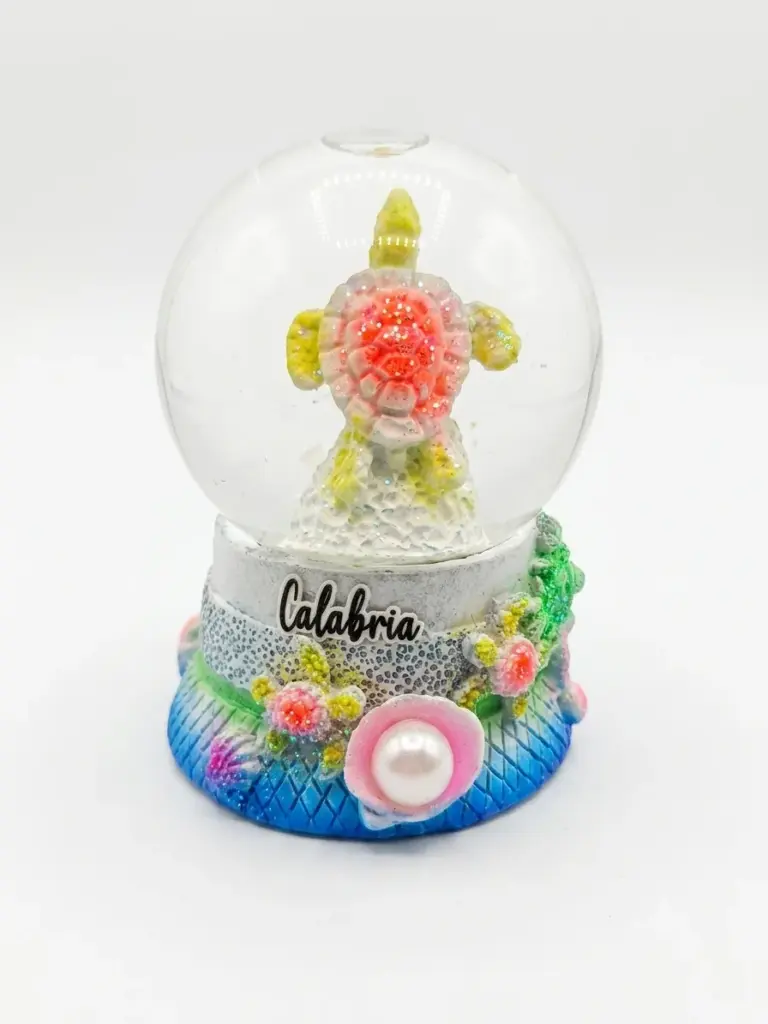Bolla di vetro con tartaruga marina in resina, guscio rosato glitterato e pinne giallo-verdi, base decorata con perla e scritta Calabria