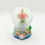 Palla di neve con tartaruga marina carapace rosa corallo e pinne verde lime, base decorata con conchiglie, alghe e perla bianca