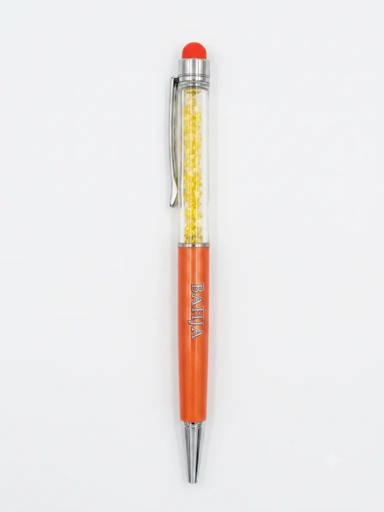 Penna a sfera arancione metallizzato con sezione trasparente e cristalli gialli, gommino arancione, clip cromata, scritta BAHJA incisa sul corpo