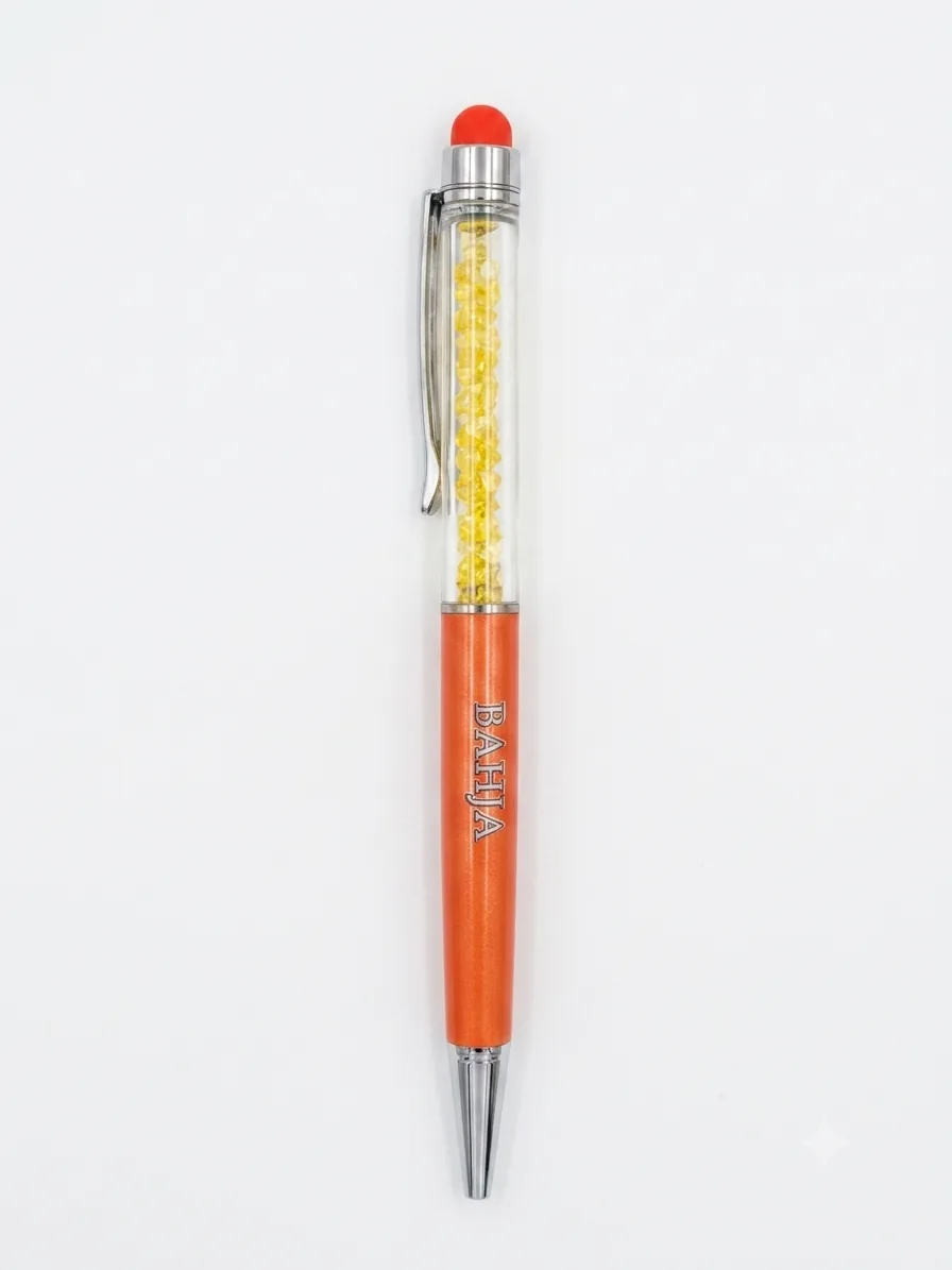 Penna a sfera arancione metallizzato con sezione trasparente e cristalli gialli, gommino arancione, clip cromata, scritta BAHJA incisa sul corpo