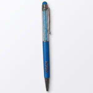 Penna a sfera con fusto trasparente riempito di cristalli azzurri, impugnatura blu con scritta Bahja incisa e puntale stilo azzurro in cima