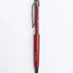 Penna a sfera rossa Bahja con corpo trasparente riempito di cristalli rossi, finiture cromate, clip laterale e gommino touch rosso in cima.