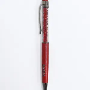 Penna a sfera rossa Bahja con corpo trasparente riempito di cristalli rossi, finiture cromate, clip laterale e gommino touch rosso in cima.
