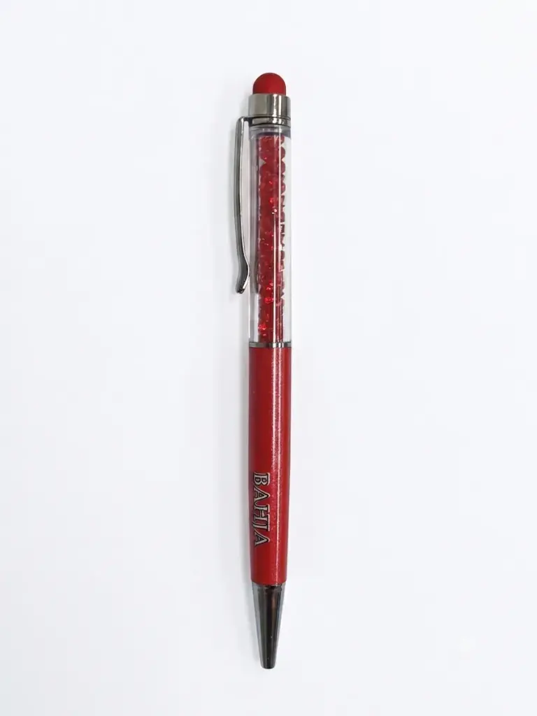 Penna a sfera rossa Bahja con corpo trasparente riempito di cristalli rossi, finiture cromate, clip laterale e gommino touch rosso in cima.