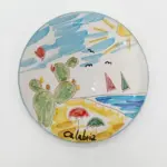 Piatto ceramica tondo con fichi d'india verdi, mare azzurro, barche a vela rosse e verdi, ombrelloni, sole e scritta Calabria