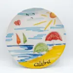 Piatto ceramica Calabria con mare azzurro, barche a vela arancio e verde, ombrelloni rosso e verde sulla spiaggia gialla, sole e gabbiani neri.