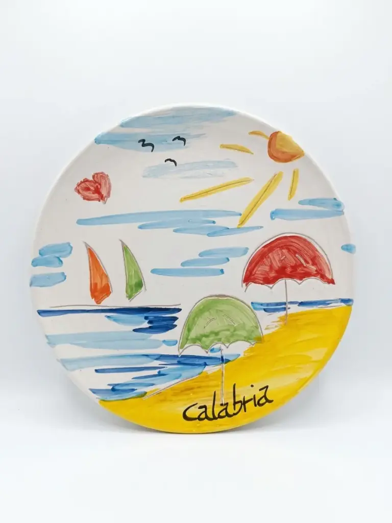 Piatto ceramica Calabria con mare azzurro, barche a vela arancio e verde, ombrelloni rosso e verde sulla spiaggia gialla, sole e gabbiani neri.