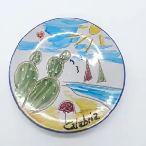 Piatto ceramica con bordo blu cobalto, spiaggia calabrese: fico d'India verde, barca a vela rosata, sole giallo, sabbia ocra e scritta Calabria