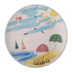 Piatto circolare in ceramica: scena balneare con barche a vela, ombrelloni rosa e verde, sole, gabbiani e scritta Calabria sulla sabbia
