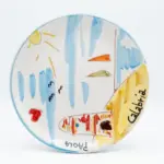 Piatto ceramica con scena marina pitturata: barche multicolori, sole giallo, gabbiani neri, cuore rosso, scritta Calabria e Paola, bordo azzurro