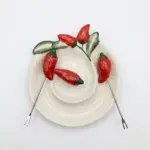 Piatto ceramica bianca a spirale con peperoncini rossi in rilievo, foglie verdi e due forchettine metalliche per aperitivo