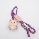 Portachiavi gattino peluche crema con orecchie e zampette viola, cordino intrecciato rosa antico, frange viola e moschettone metallico viola