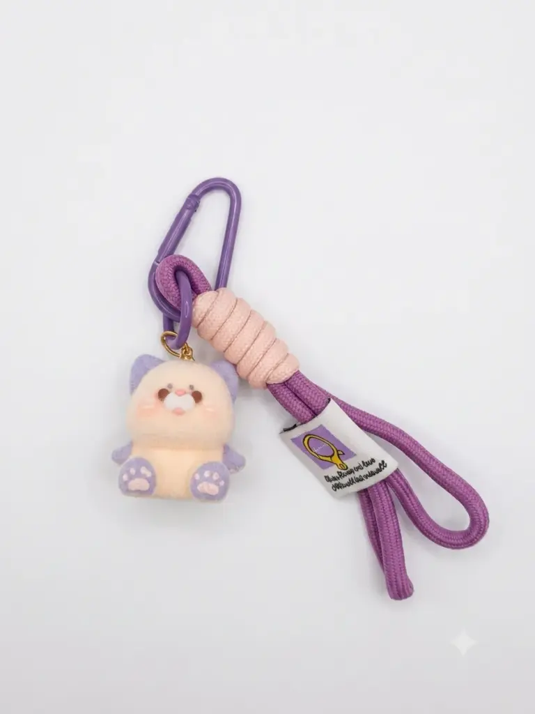 Portachiavi gattino peluche crema con orecchie e zampette viola, cordino intrecciato rosa antico, frange viola e moschettone metallico viola