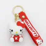Portachiavi Hello Kitty in gomma bianca con fiocco rosso seduta su mela rossa con lettera K, laccetto rosso con scritta HELLO KITTY e anello dorato