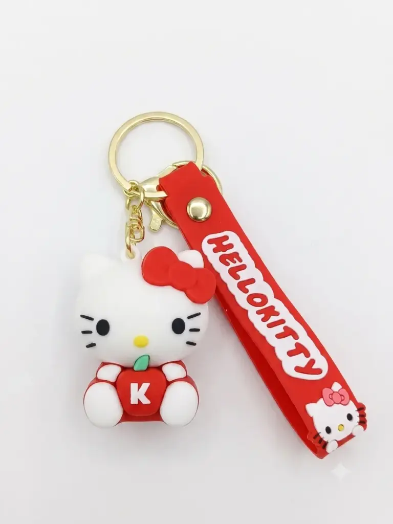 Portachiavi Hello Kitty in gomma bianca con fiocco rosso seduta su mela rossa con lettera K, laccetto rosso con scritta HELLO KITTY e anello dorato