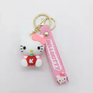 Portachiavi Hello Kitty: ciondolo bianco con fiocco rosa e mela rossa lettera K, cinturino in gomma rosa con scritta HELLO KITTY e moschettone dorato.