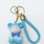 Portachiavi con orsetto in resina azzurra e bianca, texture a rilievo e fiocchetto blu cobalto, cordoncino intrecciato azzurro con hardware dorato
