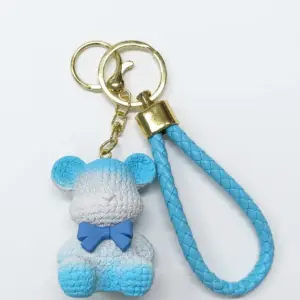 Portachiavi con orsetto in resina azzurra e bianca, texture a rilievo e fiocchetto blu cobalto, cordoncino intrecciato azzurro con hardware dorato