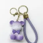 Portachiavi orsetto in resina viola lilla con texture a rilievo, fiocchetto viola al collo e cordoncino lilla intrecciato con terminale dorato