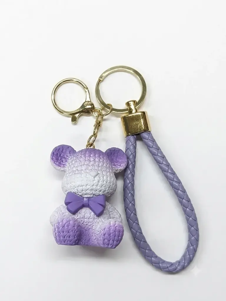 Portachiavi orsetto in resina viola lilla con texture a rilievo, fiocchetto viola al collo e cordoncino lilla intrecciato con terminale dorato