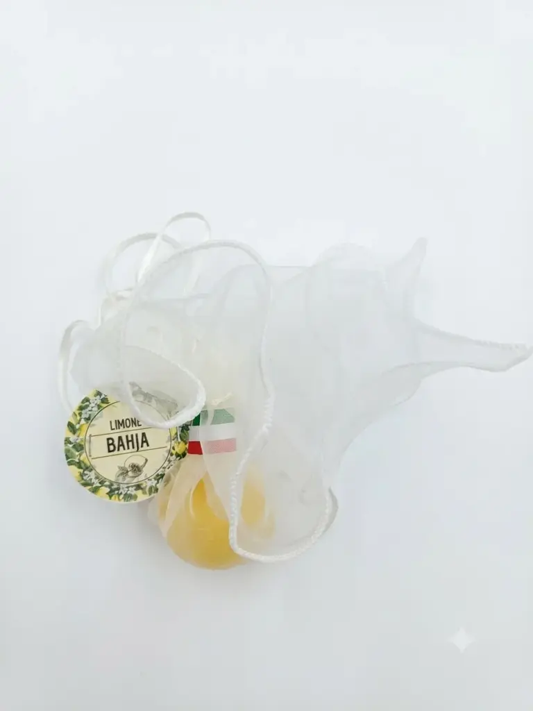 Sapone vegetale ovale giallo paglierino Bahja avvolto in organza bianca con tag rotonda Limone Bahja e nastro tricolore italiano