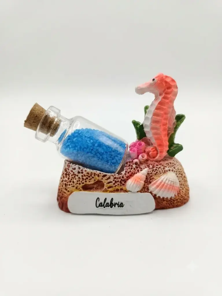 Composizione decorativa Calabria con cavalluccio marino in resina corallo, bottiglietta di vetro con sabbia blu, conchiglie e base a scoglio ocra