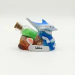 Soprammobile in resina con delfino blu su onda azzurra, bottiglietta di vetro con sabbia verde e conchiglia, targhetta Calabria