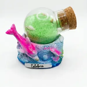 Bolla di vetro con sabbia verde brillante e tappo in sughero su base resina azzurra con delfino rosa glitterato e scritta Calabria