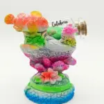 Soprammobile in resina Calabria con pesce arancione glitterato, coralli rosa, alga verde e bottiglietta vetro con scritta Calabria