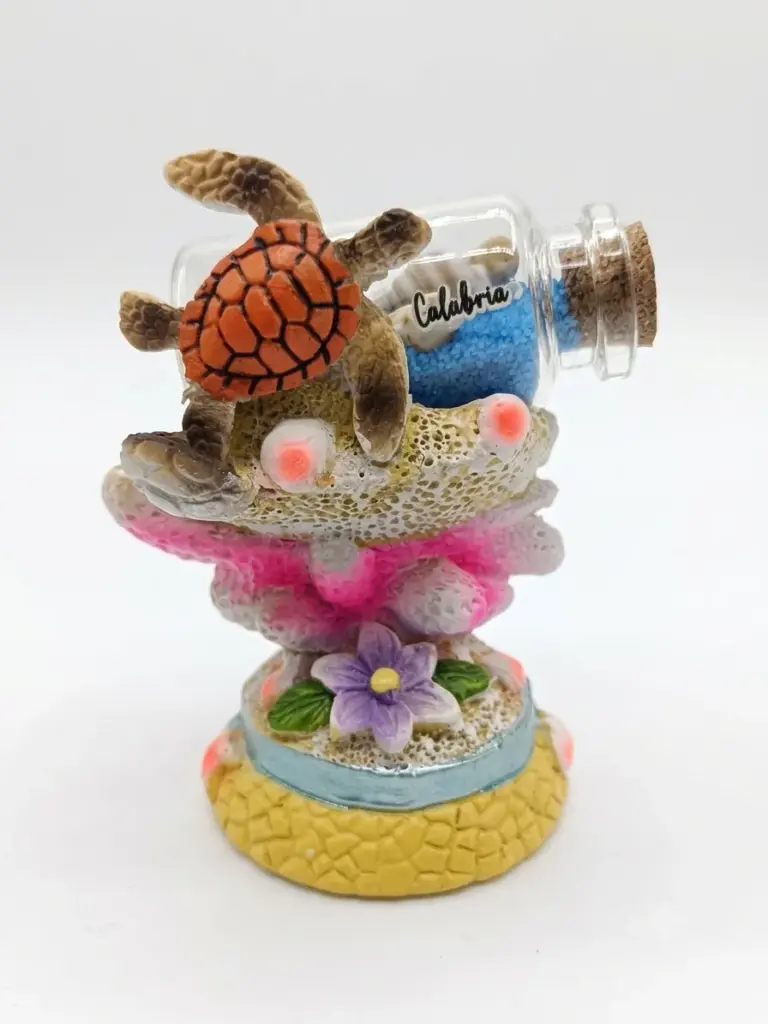 Soprammobile in resina con tartaruga marina arancione, coralli rosa-fucsia, fiore viola e bottiglia di vetro con sabbia blu e scritta Calabria