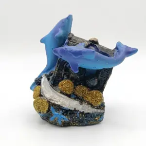Soprammobile in resina con due delfini blu e viola su relitto scuro, base glitterata dorata, stella marina azzurra e conchiglia argentata