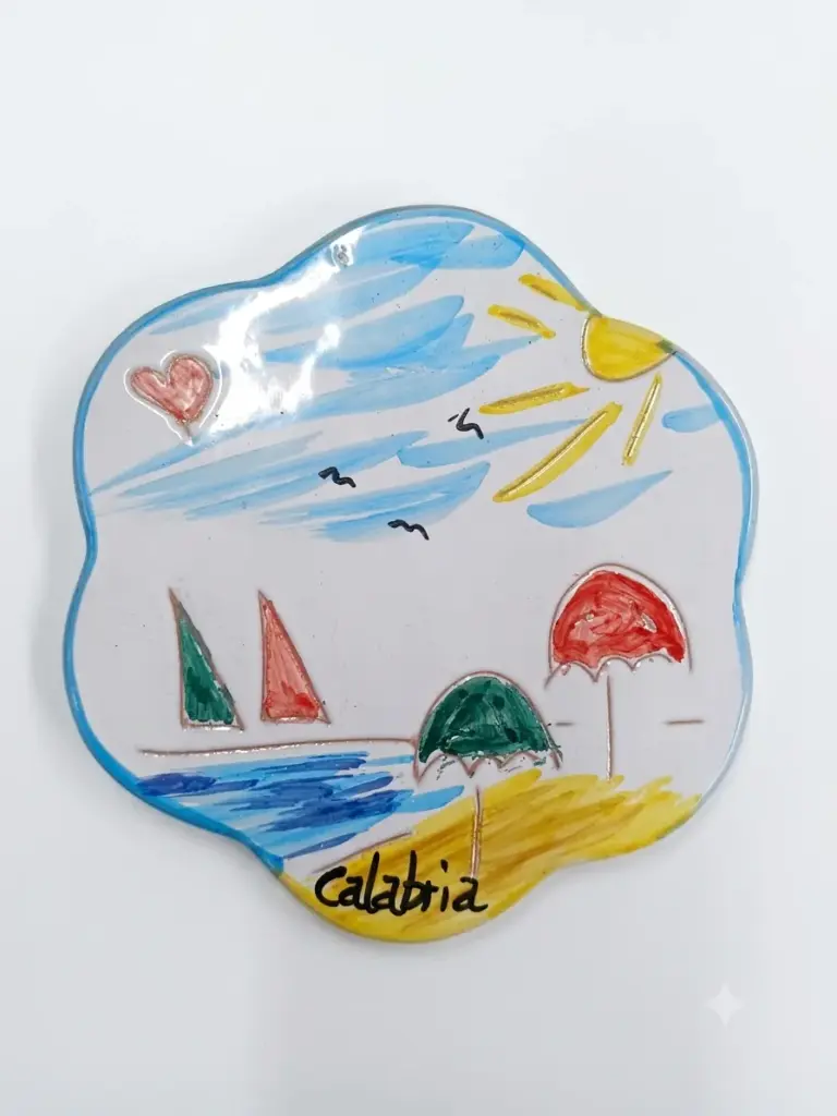 Sottopentola ceramica forma ondulata, scena marina con barca a vela, ombrelloni, sole e scritta Calabria