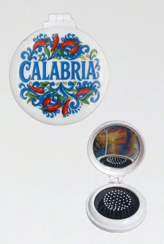 Specchietto tascabile rotondo bianco con peperoncini rossi, volute blu e scritta Calabria; interno con spazzolina nera